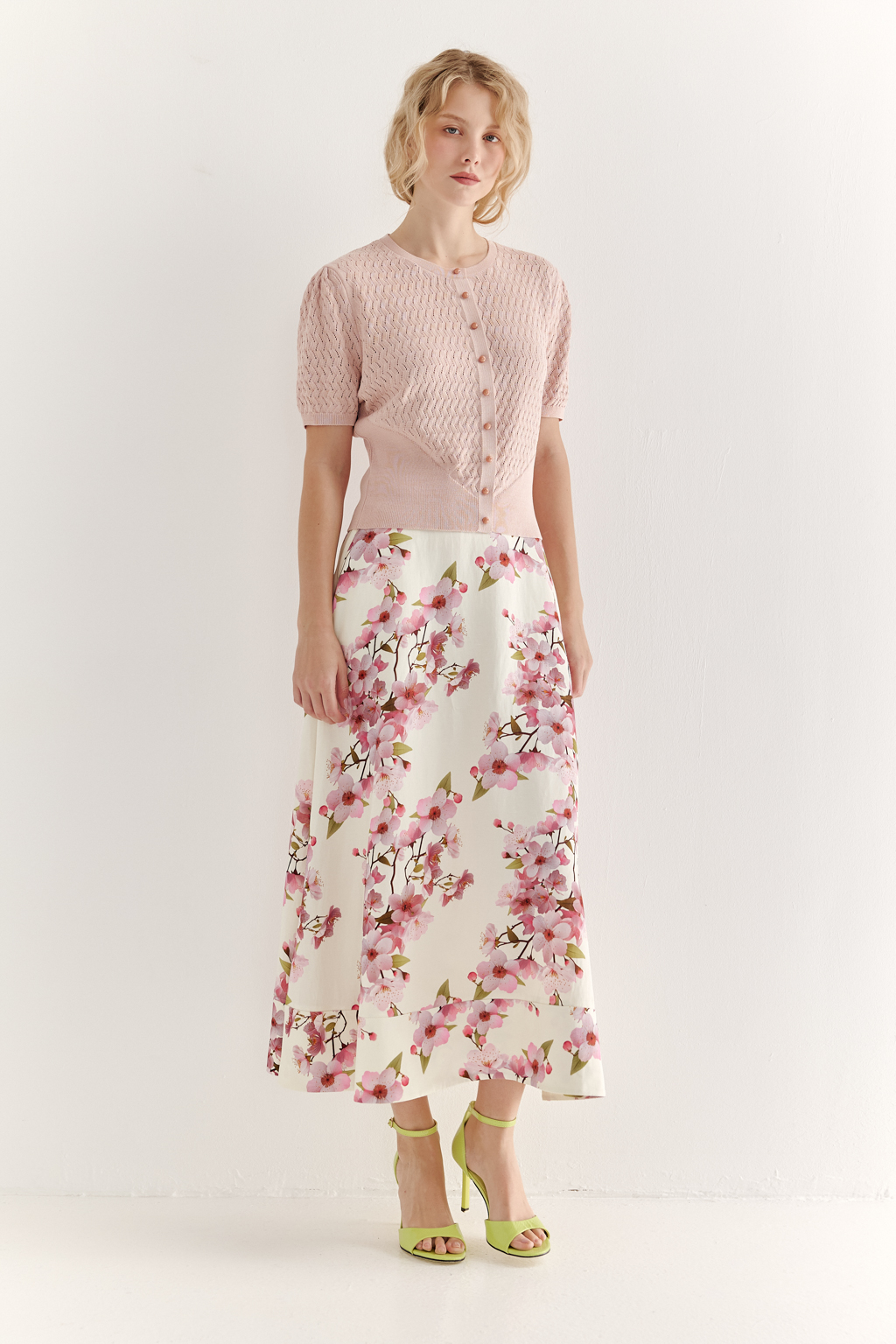 Джемпер нежно-розового цвета, связанный из тонкой тактильной пряжи, в составе которой вискоза и нейлон. В дизайне джемпера применен принцип контраста фактур, в данном случае – полупрозрачного ажура и ластика. Круглая горловина и планка с застежкой на 9 пуговиц-жемчужин, рукав длиной одна вторая.