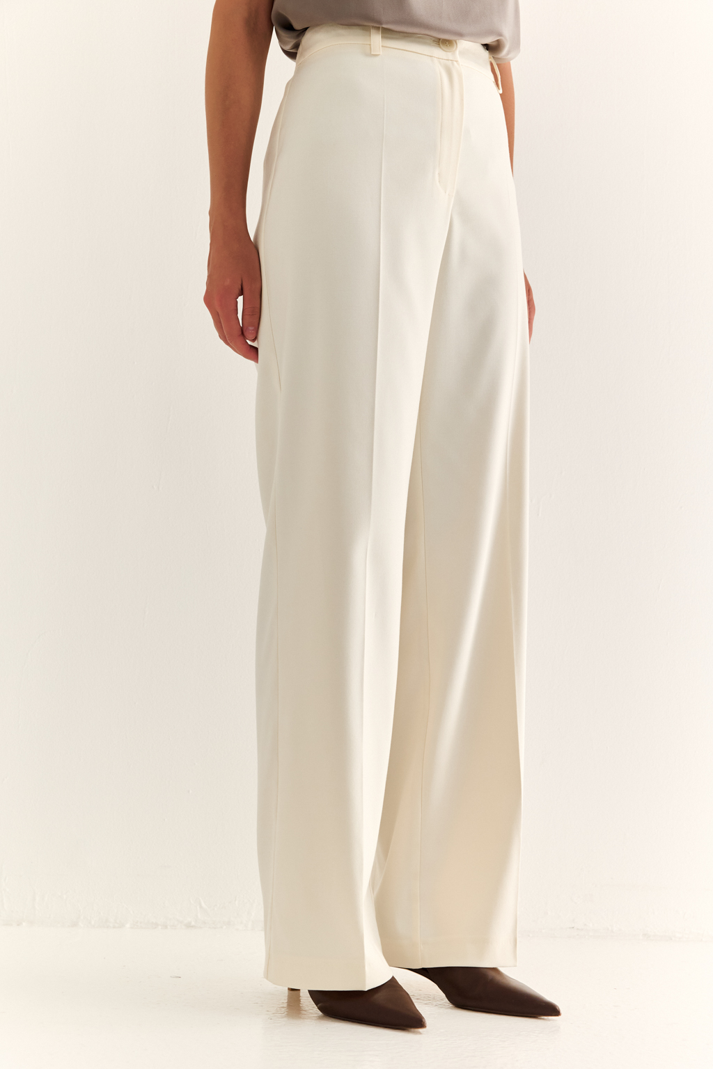 Прямые брюки: свобода, стиль, структура. Эти брюки с высокой посадкой и ровным силуэтом — воплощение современной женственности. Чёткие стрелки вытягивают силуэт, подчёркивая стройность ног, а широкие штанины добавляют образу лёгкости и статуса. Минималистичный дизайн с застёжкой на молнию и пуговицу, а также элегантный пояс делают модель идеальной для сочетания с жакетами, блузами или трикотажем. Идеальны как для офиса, так и для расслабленного городского образа. Современная классика, в которой сочетаются уверенность и комфорт.