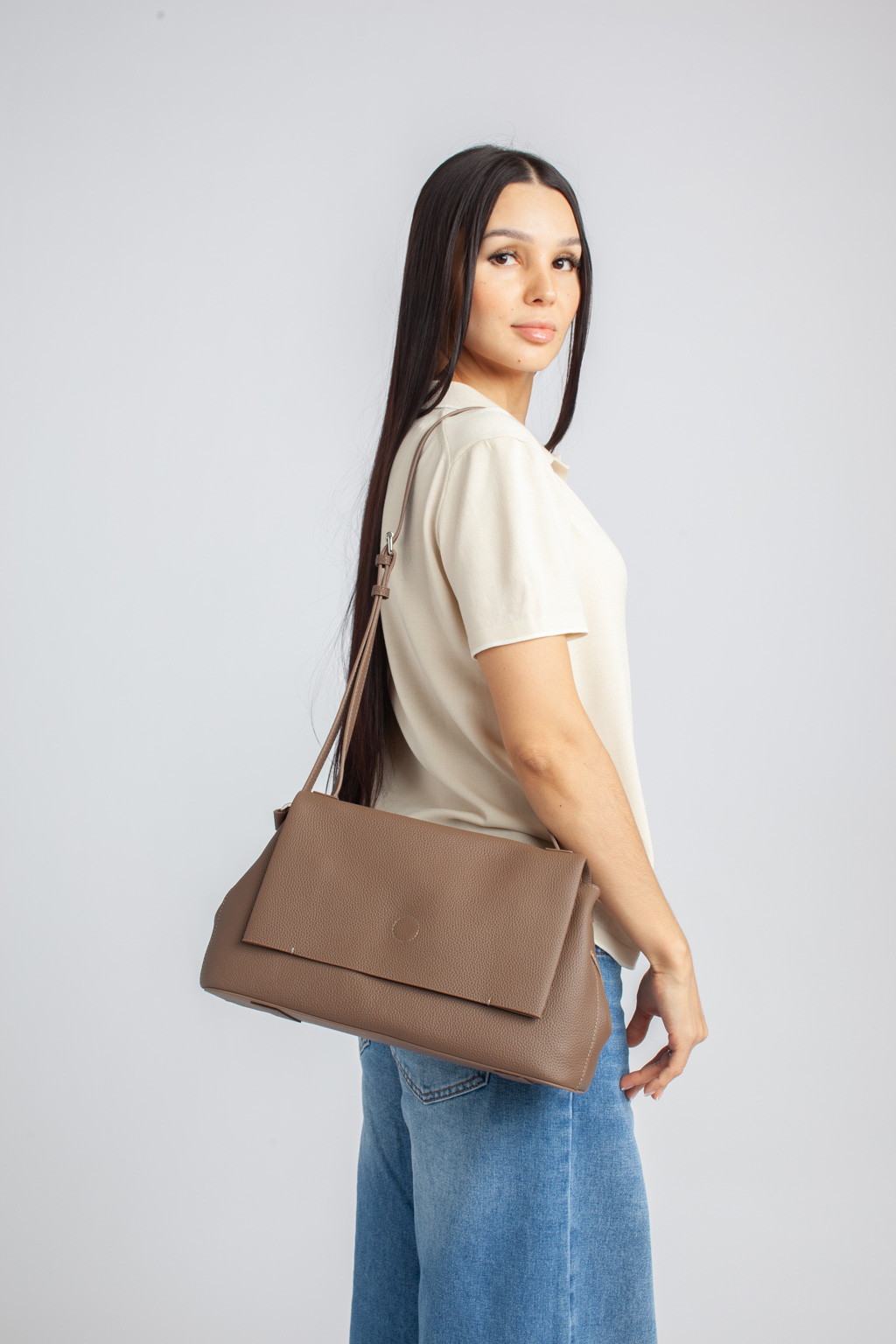 Стильная сумка на плечо в коричневом оттенке выполнена из натуральной зернистой кожи. Сумка закрывается клапаном на магнитную кнопку и на молнию. Внутри 2 отдела, разделенных средником с карманом на молнии. На внутренних боковых стенках есть 3 кармана для мелочей: 2 открытых и на молнии. На тыльной стороне предусмотрен карман быстрого доступа на молнии. В комплекте два съемных ремня для комфортного ношение аксессуара в руке и на плече , ширина 1,5 см и 2,5 см.