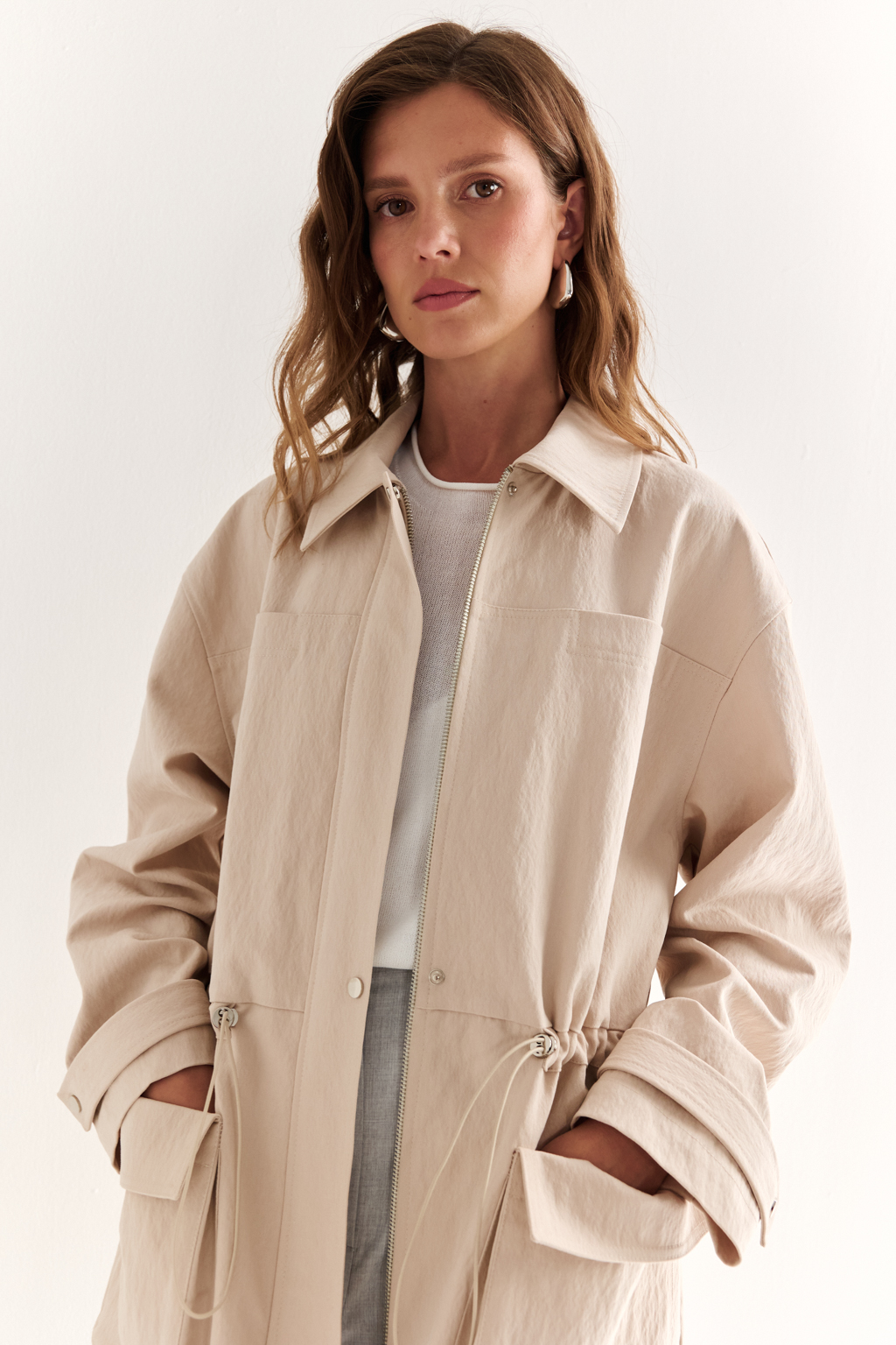 Куртка прямого силуэта длиной до бедер и с кулисой по талии. Воротник рубашечный, застежка под планкой. По полочке накладные карманы-портфели.