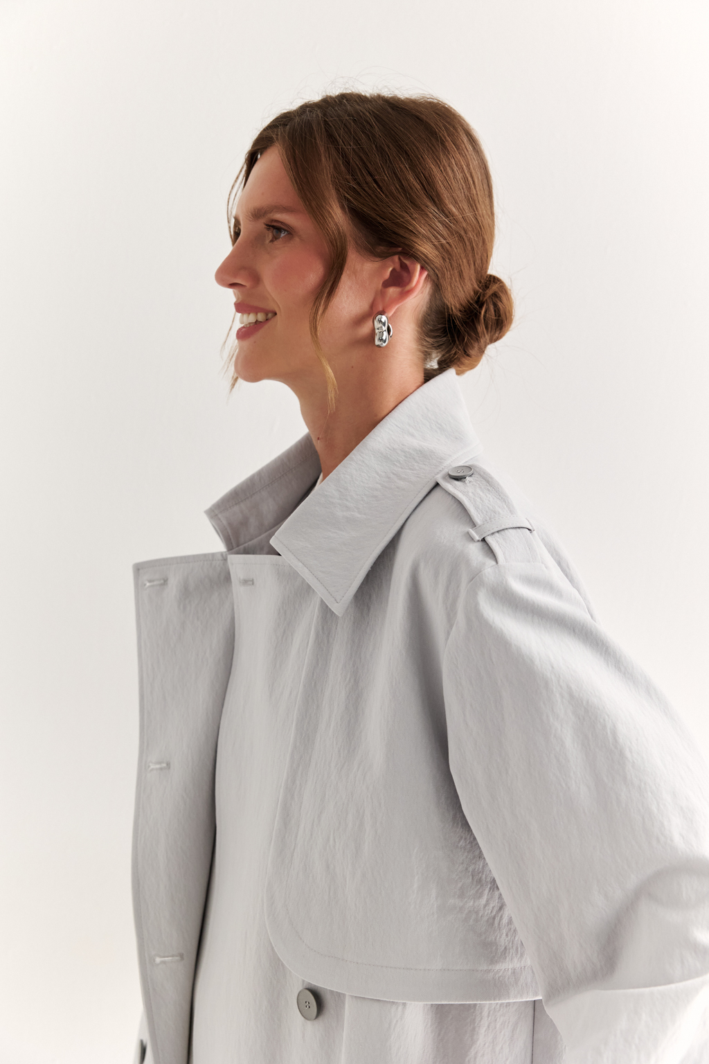 Плащ двубортный прямого силуэта длиной макси с расширенной линией плеча и отлётными кокетками по полочке и спинке. Приталивается завязывающимся поясом.