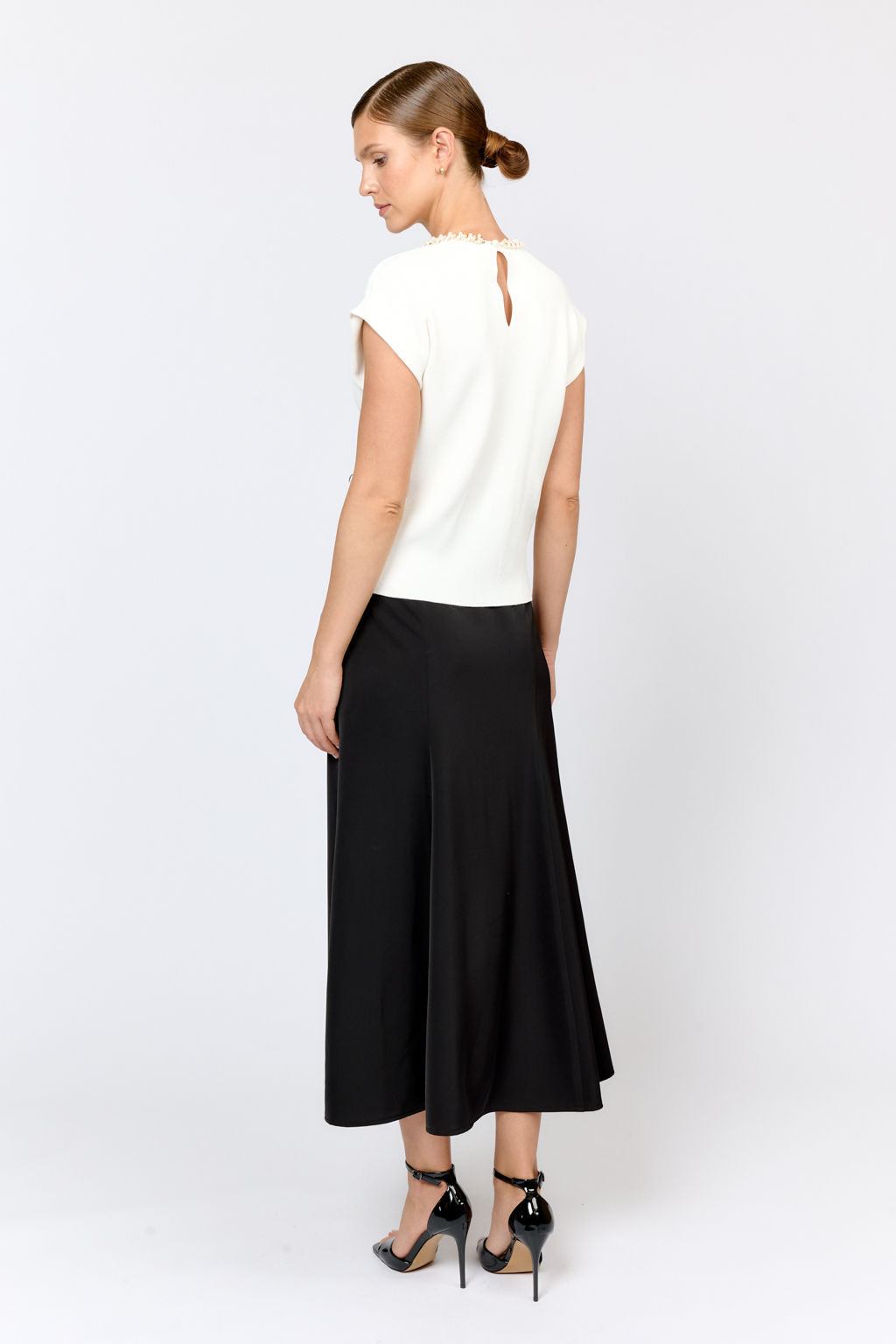 Элегантный топ  с круглой горловиной, декорированной тесьмой. Со спущенным плечом, без рукавов. Свободного силуэта. Изысканная модель из премиального  трикотажа плотной вязки в  молочном цвете. Сбалансированная комбинация вискозы и полиамида  создает комфорт при носке. Материал хорошо держит форму  и не подвержен деформации.  Лаконичный топ с декоративной тесьмой  в молочном оттенке - утонченное решение для вечерних или деловых образов.