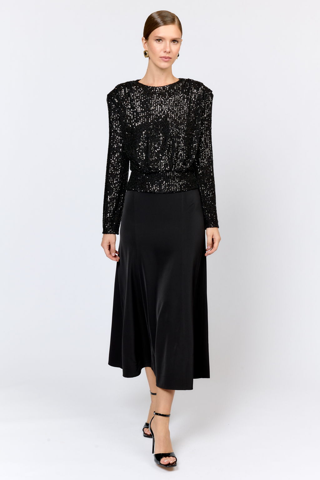 Праздничная блуза с мелкими глянцевыми пайетками с расширенной линией плеч и приталенного силуэта. По линии талии кокетка с застежкой сзади на потайные пуговицы. Ткани из полиэстера практичен в уходе, держат форму и устойчивы к сминанию. Преимущества ткани: умеренно блестящая, привлекающая  внимание ткань, для создания  эффектных образов. Пайетки придают изделиям уникальный блеск и сияние, делая их запоминающимися и праздничными.  Основа  - мягкая пластичная сетка, что делает изделие комфортным.