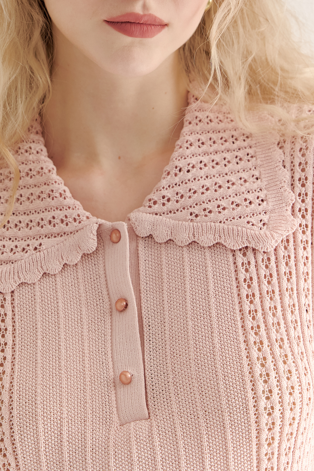 Джемпер-поло нежно-розового цвета полуприлегающего силуэта средней длины из вискозной пряжи, выполнен в комбинации полупрозрачной сетки и жаккарда, низ рукава и оторочка воротника - изящные фестоны. Рукав короткий, застежка на укороченной планке горловины на три пуговицы.