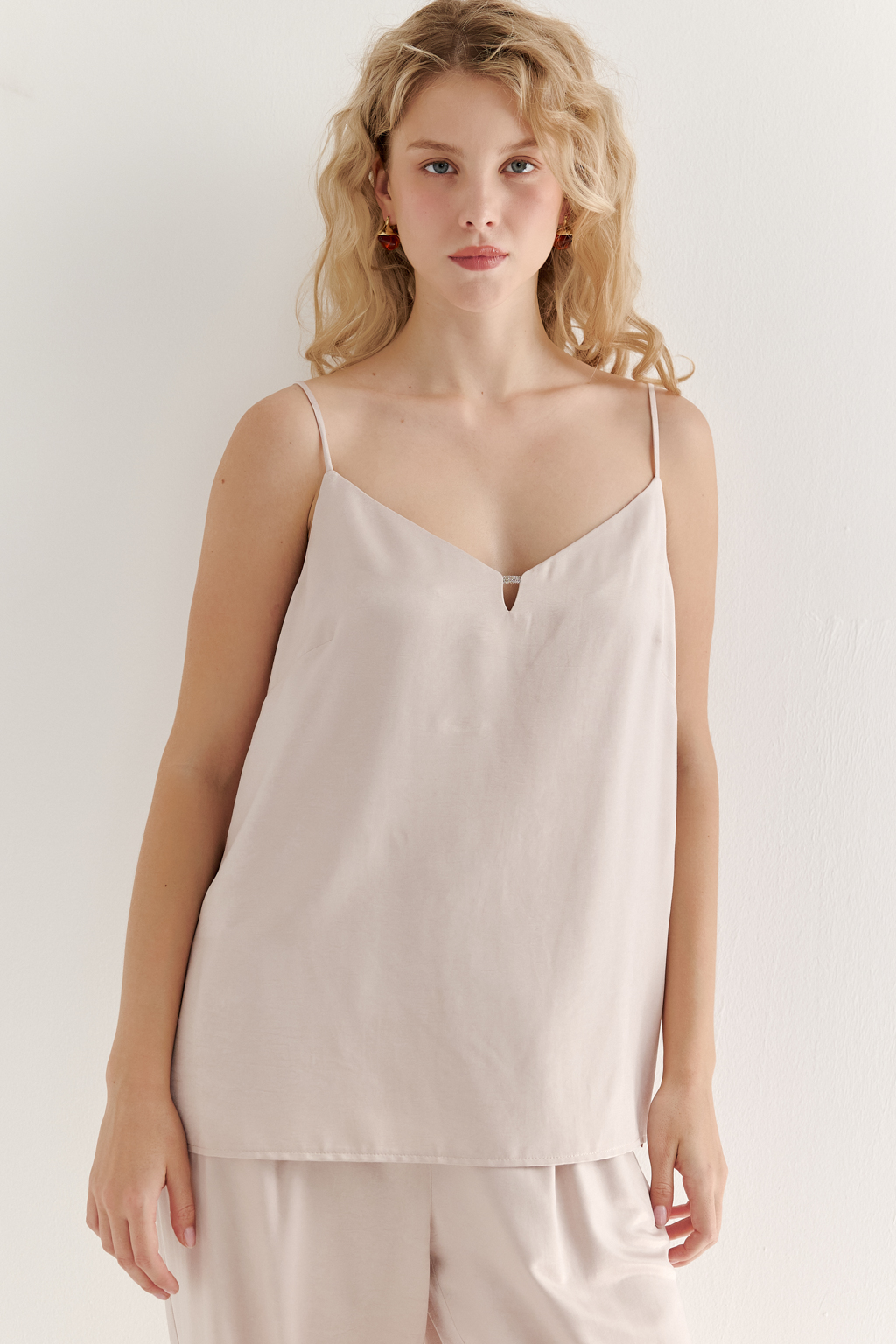 Топ из струящегося атласа с крэш эффектом в пудровом цвете. Топ на регулируемых бретелях свободного кроя с декором на линии декольте.