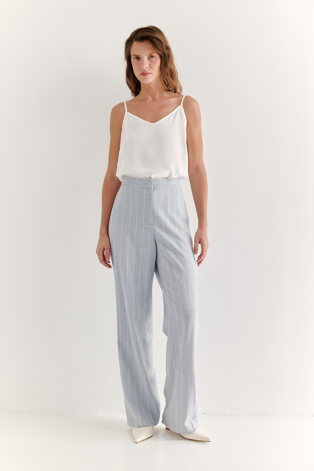Эти брюки прямого силуэта созданы для абсолютного комфорта и расслабленной элегантности. Выполненные из ткани премиум-класса, они дарят невероятное ощущение мягкости, а нежный небесно-голубой оттенок эффектно подчеркнут светлой полоской в широком раппорте. Средняя посадка и удобные карманы делают их идеальными для любого типа фигуры. Ткань с оригинальным дизайном – эксклюзивная разработка бренда. Состав: хлопок, вискоза, эластан; за долговечность отвечает полиэстер. Брюки идеально дополнят городской look с жакетом архитектурного кроя их этой же ткани, создавая модный многослойный образ.