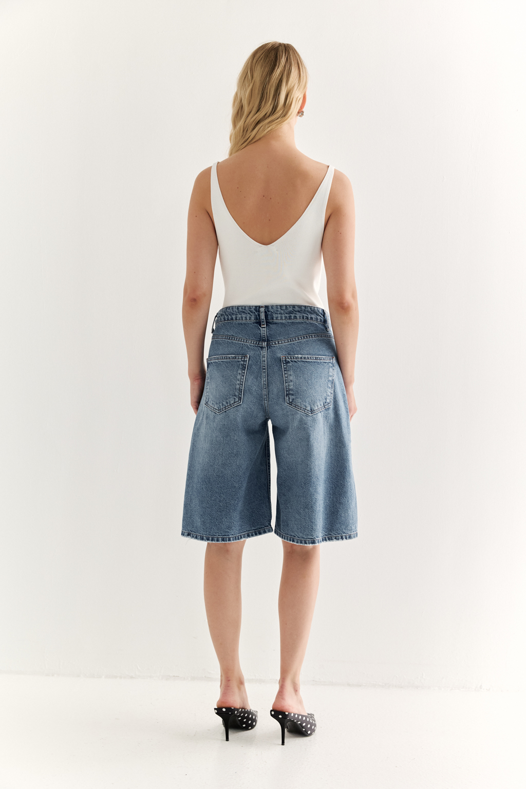 Широкие женские джинсовые шорты ниже колена из легкого денима в синем цвете. Эффект легкой потертости придаст образам расслабленности.