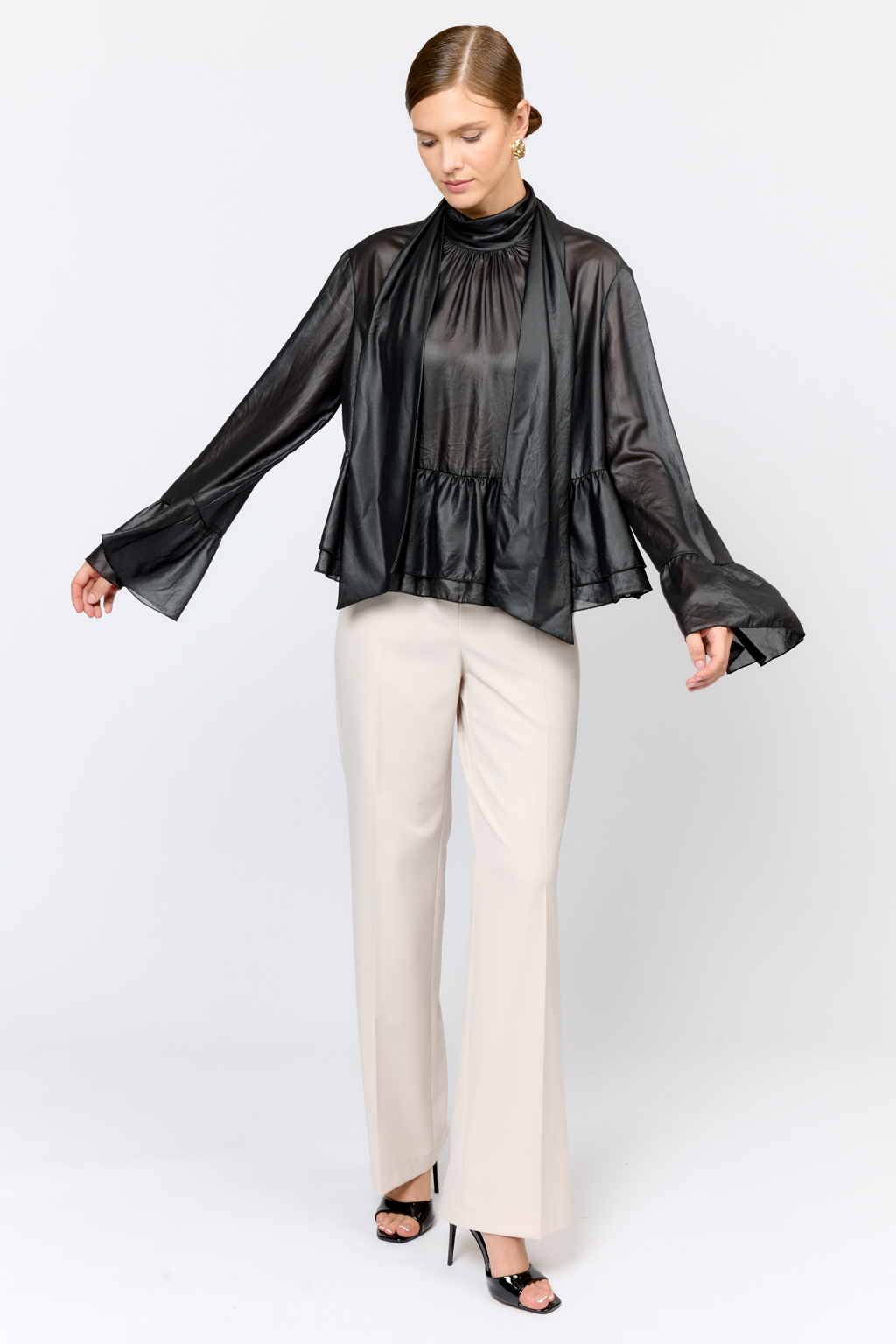 Блуза свободного кроя с летим расширением книзу с воланами по низу и воротником-стойкой, переходящим в ленты, которые можно завязать в бант либо просто перекинуть через плечи. Выполнена из легкой полупрозрачной ткани с глянцевым напылением, создающим эффект кожи. Полиэстер легкий и воздушный материал, создающий ощущение невесомости, практичен в уходе,  устойчив к сминанию. Преимущества ткани: высокотехнологичный материал премиального качества с оригинальным напылением, имитирующим кожу. Ткань пластично драпируется и красиво движется. Приглушенный блеск придает образу нарядность, а необычная фактура делает его стильным.