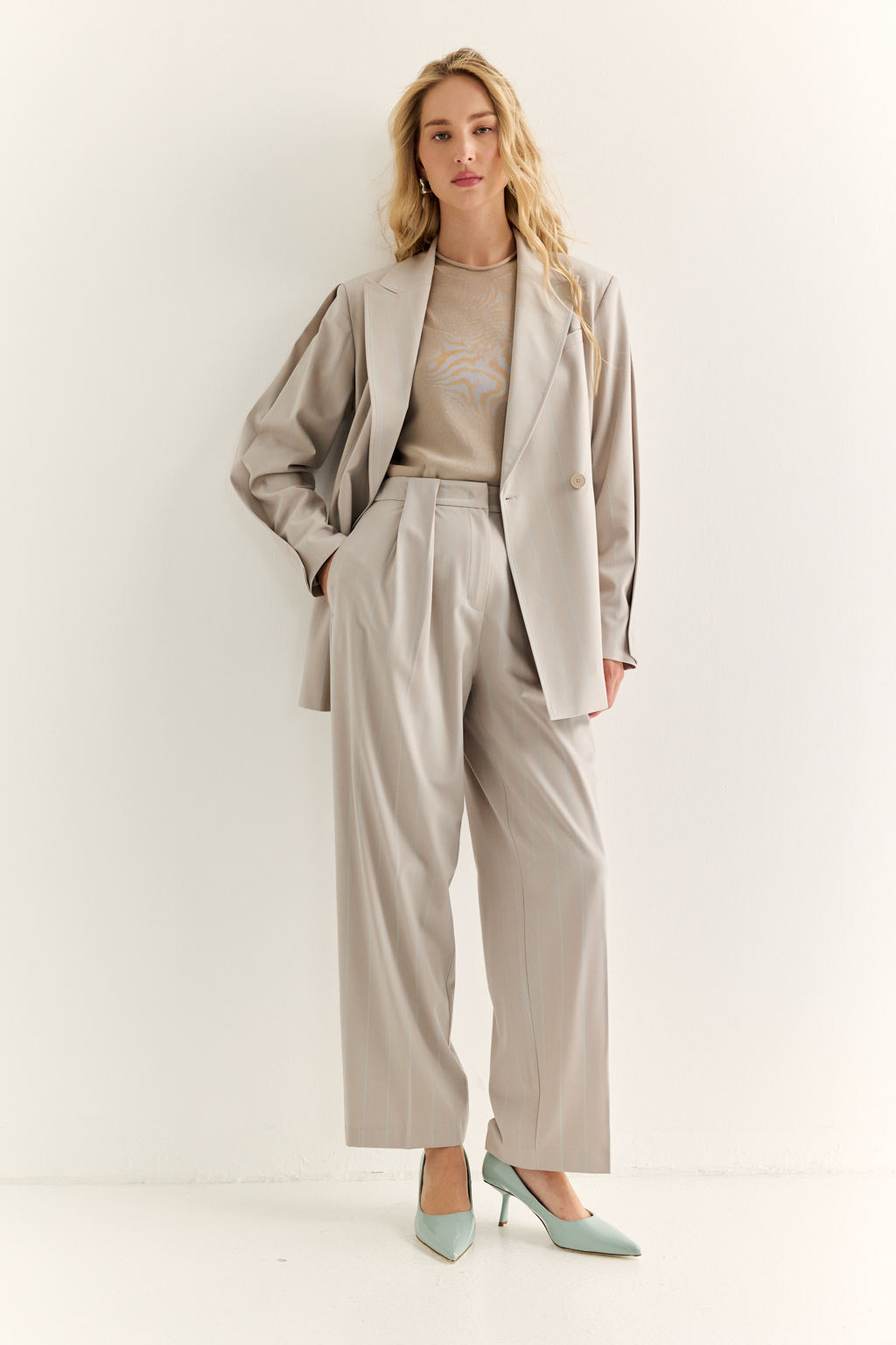 Брюки со складками: актуальный силуэт и комфорт с характером. Эти брюки с высокой посадкой и мягкими складками от талии — отличный баланс между классикой и современностью. Складки добавляют объёма и свободы в движении, формируя красивую линию бедра, а зауженные книзу штанины подчёркивают динамичность образа и визуально стройнят. Прорезные карманы сзади, шлёвки под ремень и точный крой делают модель универсальной: носите с жакетами, блузами или базовыми топами — от офиса до неформальных выходов. Гармония объёма и структуры. Брюки, которые работают на вашу фигуру.