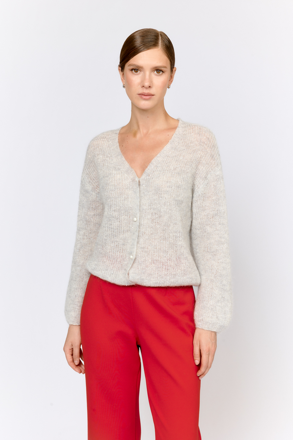Кардиган с центральной застежкой на пуговицы, V-образной горловиной и длинным рукавом.  Модель свободного силуэта в жемчужно-сером  оттенке из воздушной пряжи с шерстью и мохером с деликатными мелкими пайетками, придающими легкое сияние. Кардиган очень теплый, несмотря но свою трендовую транспарентность и легкость, благодаря мохеру в составе. Шерсть так же обеспечивает естественную терморегуляцию и уют. Такой кардиган будет выигрышно смотреться в образах с  брюками и юбками из коллекции, а так же дополнит образы с платьями на бретелях или платьем-бандо.