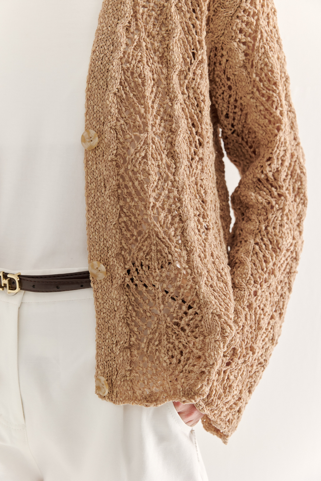 Бежевый вязаный кардиган оверсайз силуэта из хлопковой пряжи. Кардиган связан в сложной технике комбинирования сетки и ажурных ромбов. Рукав прямой удлиненный, V-образный вырез, борт отделан планкой, застежка по борту на 3 пуговицы, низ кардигана и рукав – сложные фестоны.