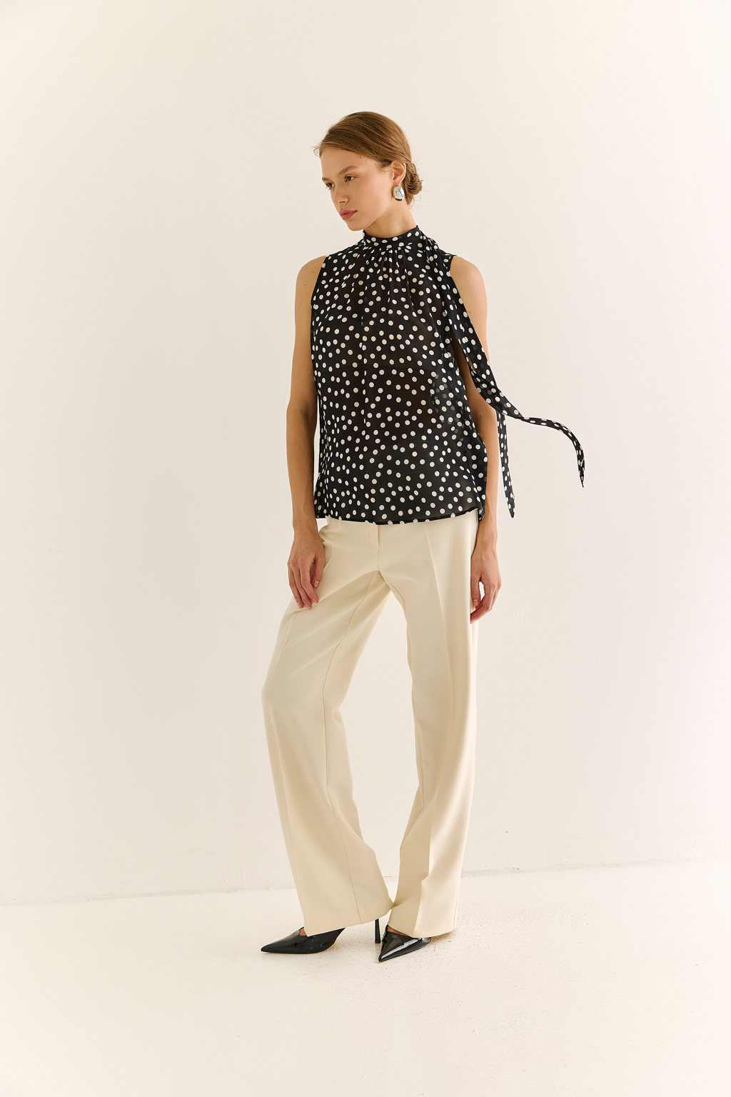 Блузка с бантом: женственность и утончённый акцент. Эта блузка без рукавов — воплощение элегантной простоты с выразительной деталью. Горловина украшена мягким бантом, который добавляет образу нотки утончённости и романтичного шика. Лёгкая драпировка спереди делает силуэт свободным, но изящным, подчёркивая вкус и стиль. Идеальна для офисных будней, деловых встреч или вечерних образов. Эффектно смотрится под жакет или кардиган, но и сама по себе становится акцентом. Сила — в деталях. Женственность — в каждом движении.