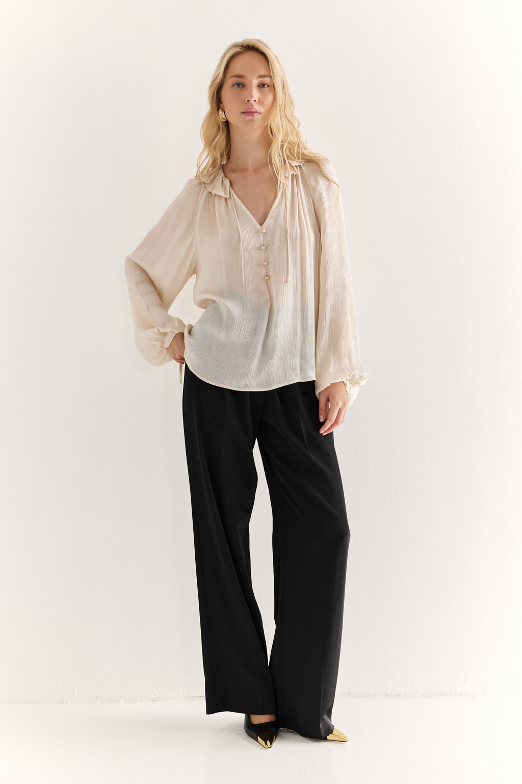 Блуза из 100% шёлка: воздушная элегантность с характером. Эта блуза создана из натурального шёлка — благородной ткани, которая буквально скользит по коже и придаёт образу утончённость. Объёмные рукава с  завязками создают лёгкий силуэт, а мягкая рюша по линии горловины добавляет динамики и изящества. Прямой крой обеспечивает комфорт и универсальность: блуза легко адаптируется под офисный стиль, романтичные образы или вечерние выходы. Носите с классическими брюками, юбками или джинсами — она всегда выглядит достойно. Чистый шёлк. Чистая элегантность.