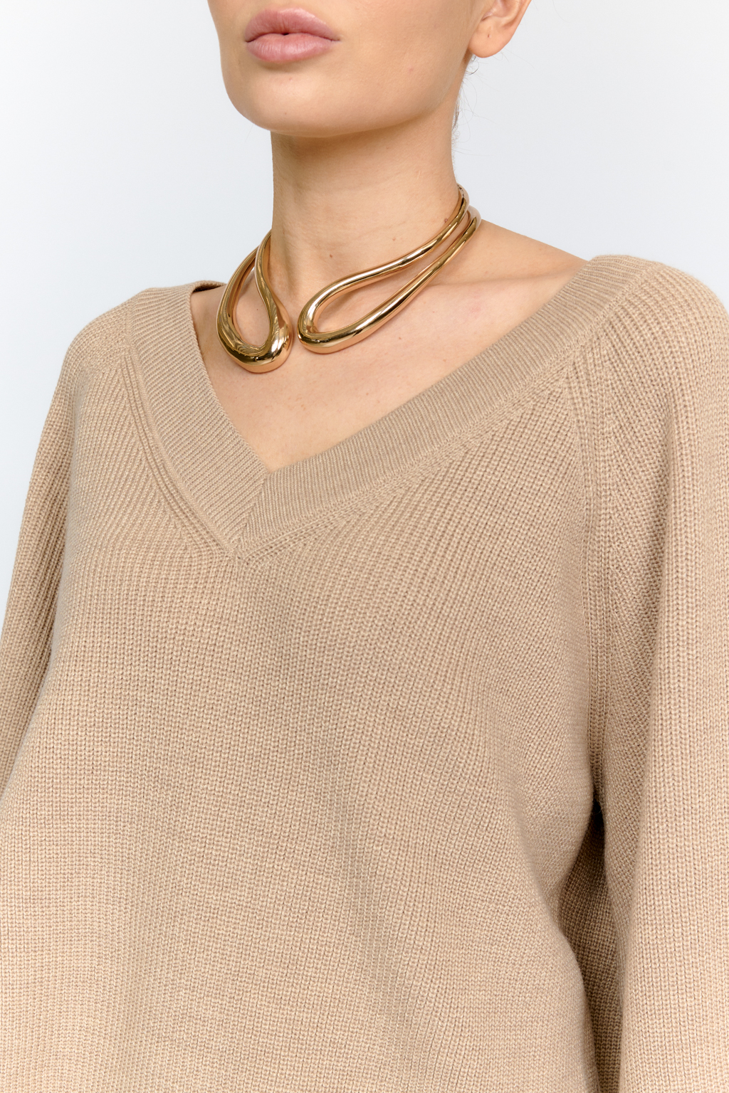 Трикотажный джемпер бежевого цвета свободного силуэта с V-образным вырезом горловины и рукавами реглан из шерстяной смесовой пряжи станет центром комфортных осенних образов.