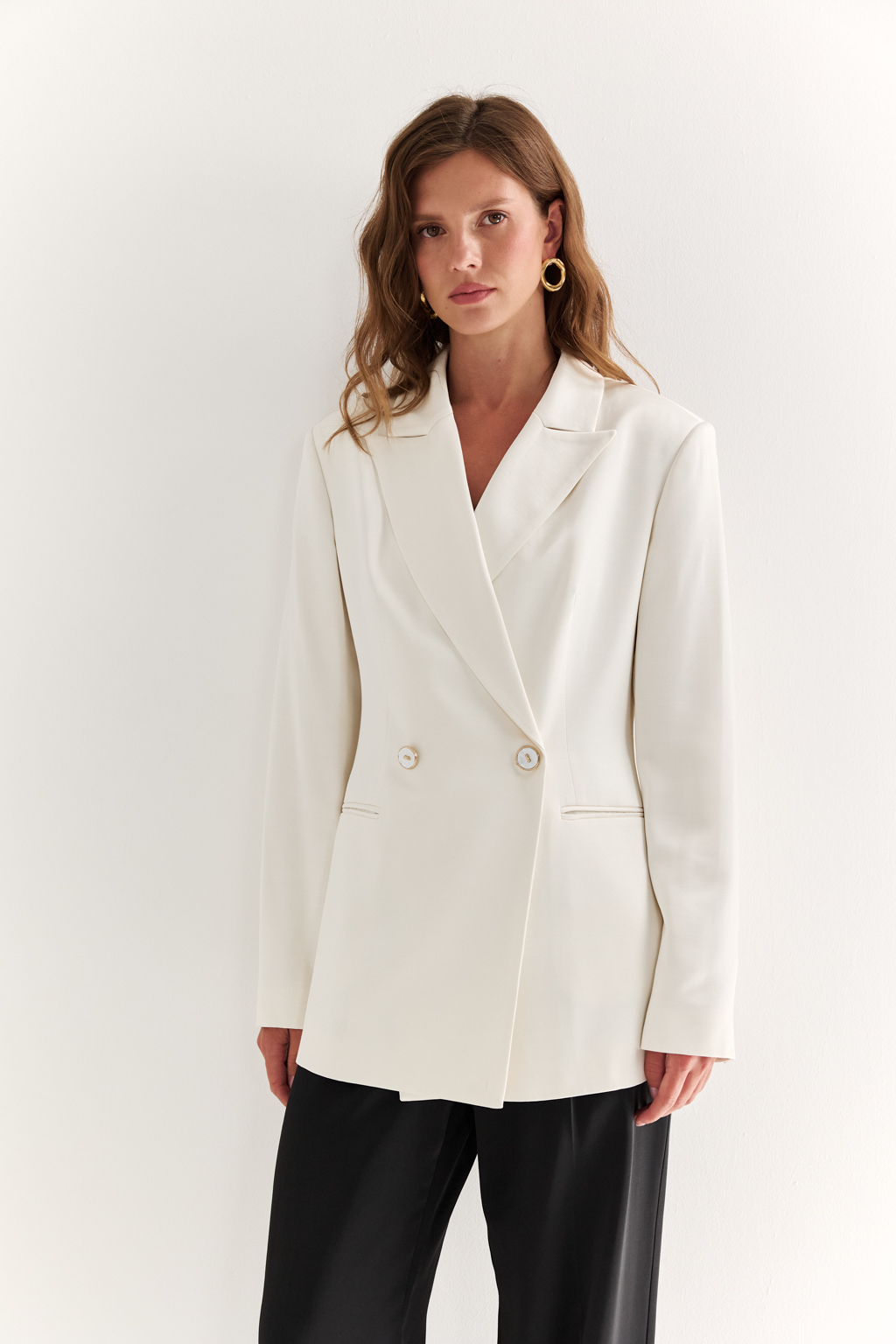 Двубортный жакет: классика в современной геометрии. Удлинённый двубортный жакет — это база, которая говорит о статусе без слов. Чёткие плечи, графичный крой и острые лацканы формируют уверенный, собранный образ. Рельефы по спинке и бокам подчёркивают силуэт, обеспечивая идеальную посадку, а карманы добавляют практичности и сдержанного акцента. Идеален в паре с классическими брюками, юбкой-карандашом или джинсами. Работает как в деловом комплекте, так и в вечерней стилизации. Современная структура с уважением к традиции.