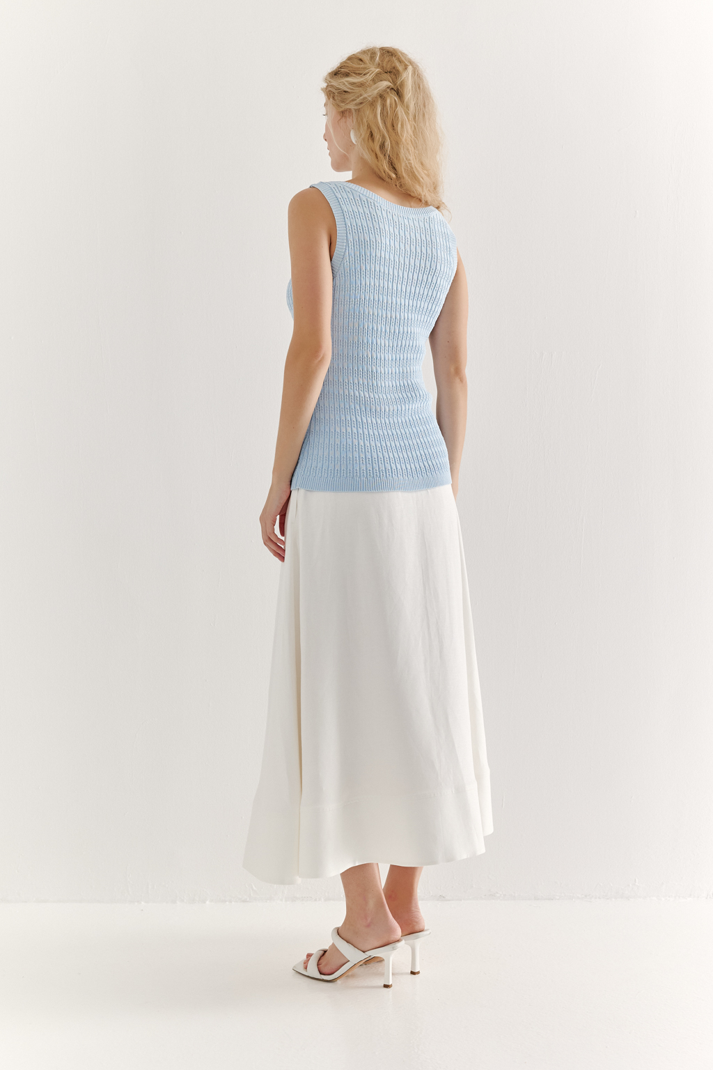 Фактурный топ-майка прилегающего силуэта из вискозной пряжи связана косами, проймы и горловина отделаны вязанными кантами. Цвет – голубой.