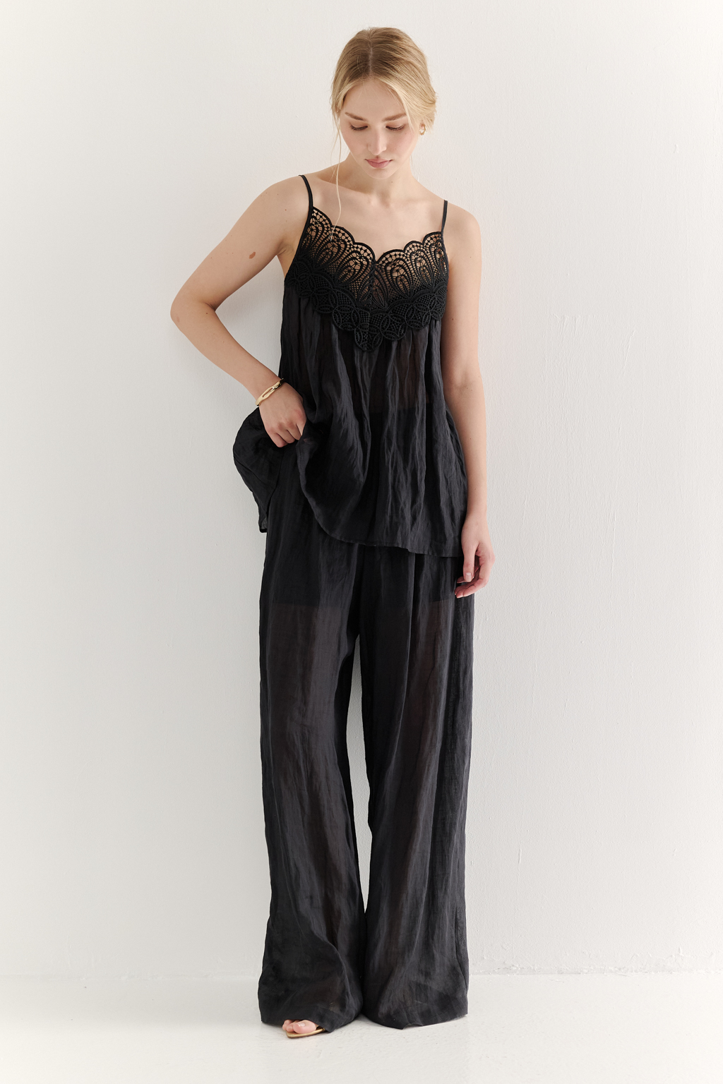 Топ-трапеция, выполненный из стопроцентной крапивы с крэш эффектом в черном цвете, украшен отделкой из кружевного гипюра в тон основной ткани. Кружевная деталь изысканно располагается на передней части изделия. Деталь переда топа настрочены на кружево со сборкой, по верхнему срезу спинки предусмотрена резинка, обеспечивающая оптимальную посадку. Бретели топа регулируются. Топ представляет собой идеальный комплект с брюками из крапивы, льна или хлопка, создавая гармоничный и стильный образ. Хранить в свернутом состоянии.