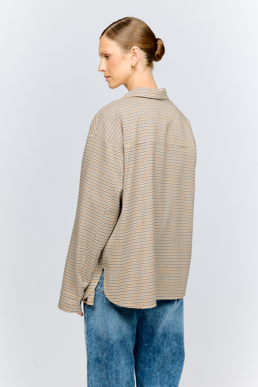 Рубашка свободного кроя с накладными карманами и застежкой на металлические пуговицы-болты из клетчатой костюмной ткани идеальна как для многослойных образов с футболками и водолазками, так и в качестве самостоятельной единицы.