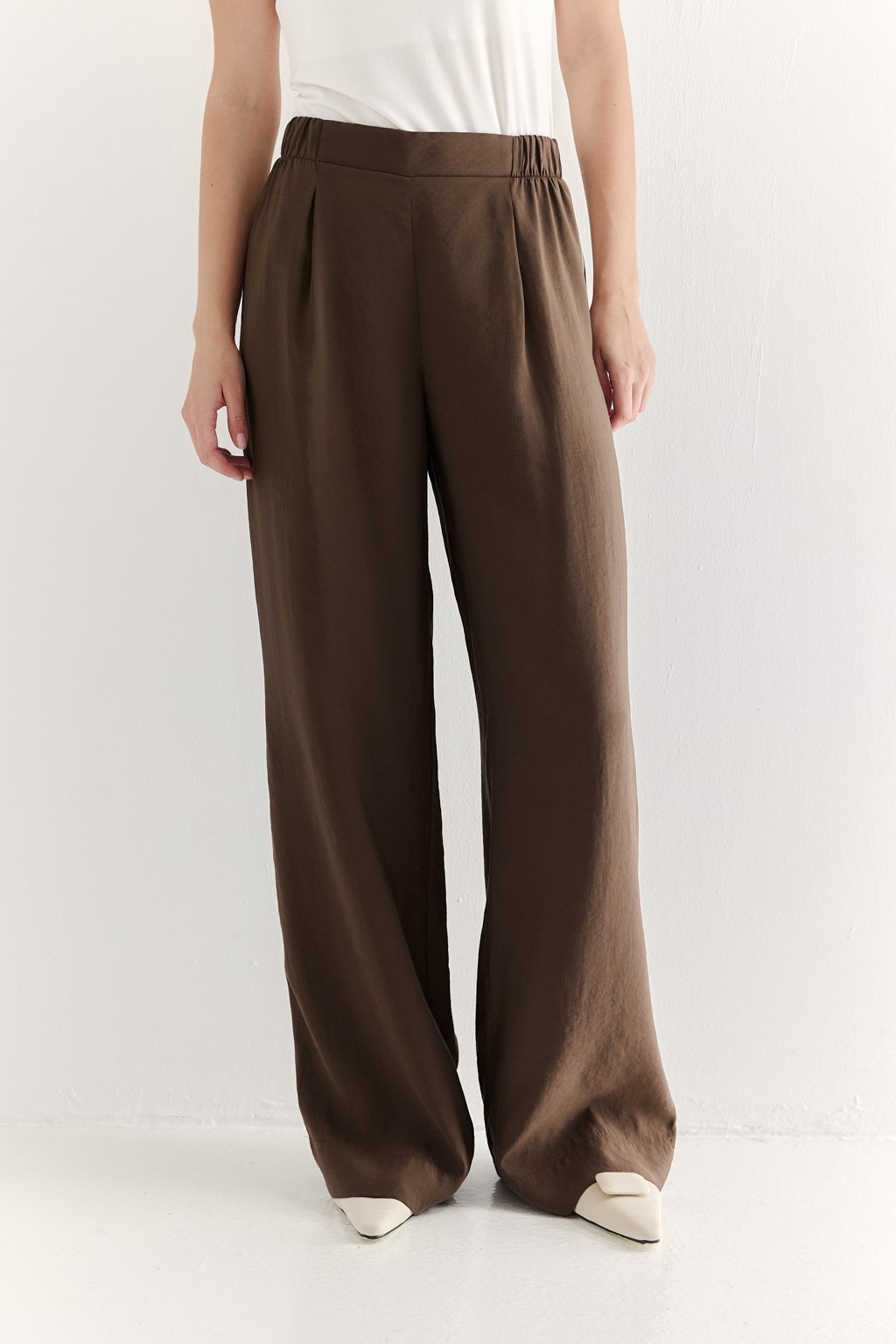 Эти широкие брюки свободного кроя, выполненные из мягкого модала насыщенного шоколадно-коричневого оттенка. Бархатистая текстура ткани, созданная благодаря особой обработке, дарит неповторимое ощущение нежности, тактильно напоминая прикосновение к кожице спелого персика – тот самый «Peach эффект». Боковые швы брюк обработаны шелковистым кантом молочного цвета. Эластичный пояс и удобные боковые карманы обеспечивают исключительный комфорт. Брюки идеально сочетаются с блузой из аналогичной ткани, создавая гармоничный ансамбль, а также с компактными трикотажными блузами и топами светлых оттенков, позволяя создавать множество стильных образов.