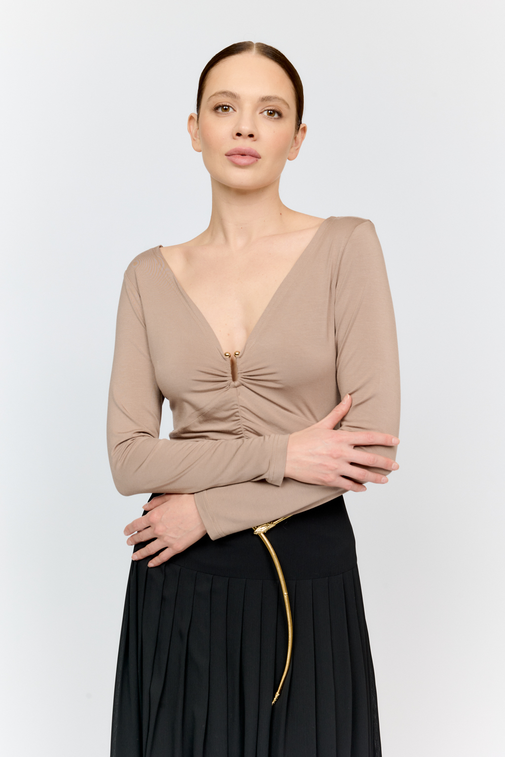 Лонгслив в цветет тофу с глубоким V-образным вырезом горловины и декором из металла в золотом оттенке. Спереди ткань драпируется в области груди и по средней линии полочки. Изделие подарит приятные тактильные ощущения в носке. Подойдет для стилизации со множеством образов.