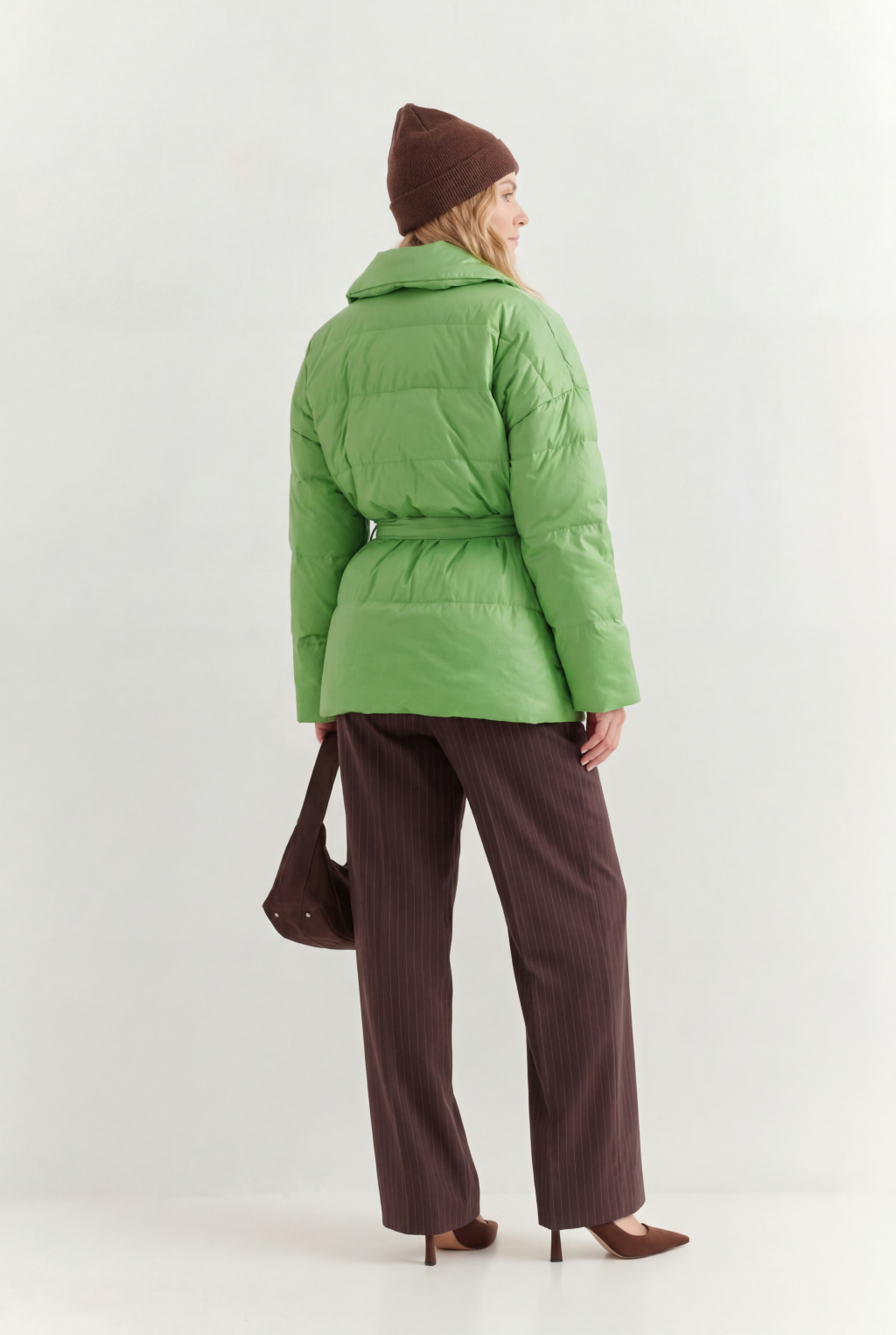Короткий стеганый пуховик с английским воротником в цвете зеленой мяты, застегивается на кнопки, имеет регулируемый пояс, что позволяет носить изделие в разных вариациях.