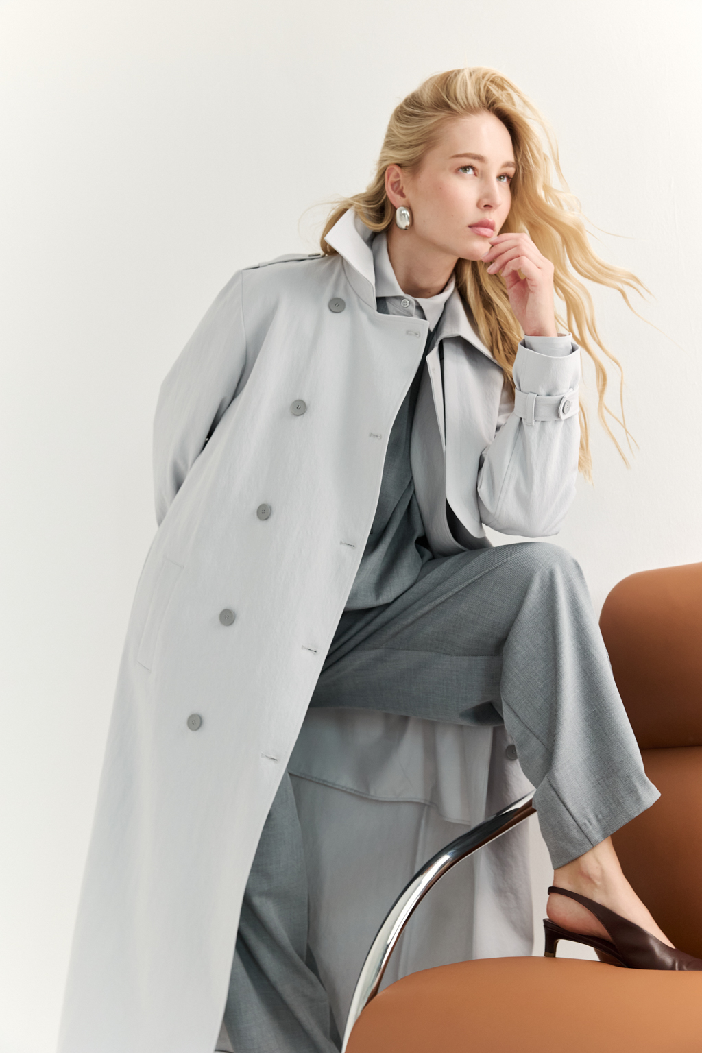 Плащ двубортный прямого силуэта длиной макси с расширенной линией плеча и отлётными кокетками по полочке и спинке. Приталивается завязывающимся поясом.