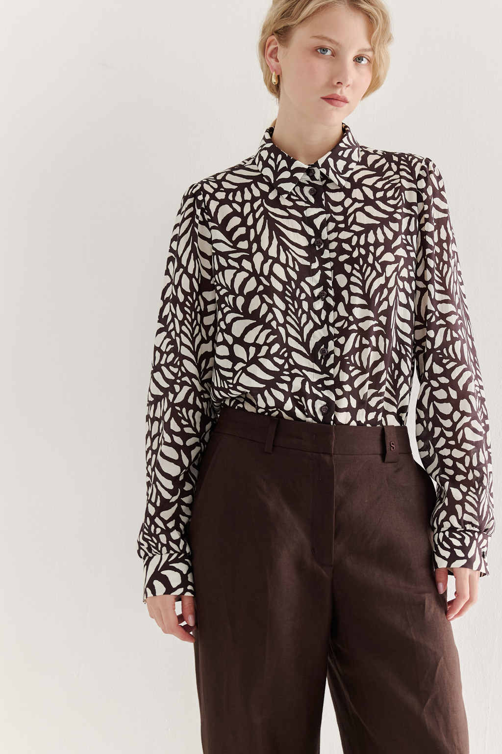 Блуза из легкой блузочной ткани с эффектом шелка со стилизованным растительным принтом в шоколадно-молочной гамме. Комфортная блуза имеет рубашечный воротник со стойкой, длинный рукав с манжетами, застёгивается на пуговицы.