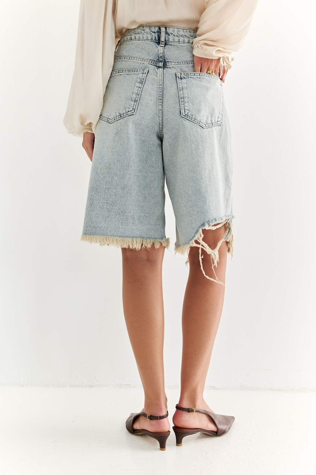 Широкие женские джинсовые шорты ниже колена из легкого денима. Рваные края придают изделию оригинальности.