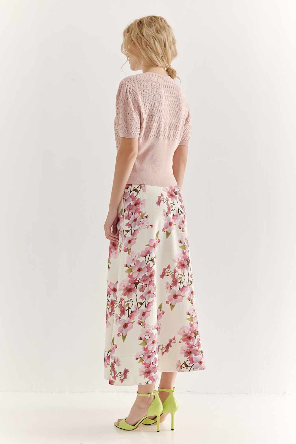 Джемпер нежно-розового цвета, связанный из тонкой тактильной пряжи, в составе которой вискоза и нейлон. В дизайне джемпера применен принцип контраста фактур, в данном случае – полупрозрачного ажура и ластика. Круглая горловина и планка с застежкой на 9 пуговиц-жемчужин, рукав длиной одна вторая.