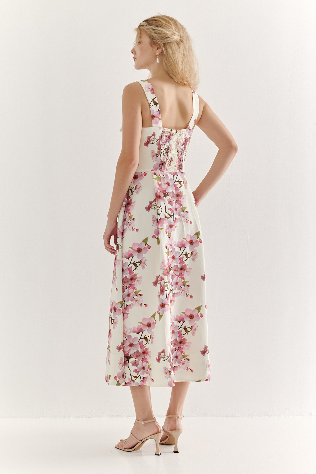 Платье-сарафан полуприлегающего силуэта выполнено из плотной пластичной ткани в основе которой волокна вискозы и льна. Лиф-бандо, акцент на линию талии и юбка полусолнце формируют изящный Х-образный силуэт. Особую утонченность платью придают бретели сложной формы, изящно завязывающиеся на шнуры. Эластичная деталь на спинке платья, собранная на нити-стрейч, и застежка-молния в боковом шве обеспечивают комфортную и превосходную посадку по фигуре. Ключевой деталью, выделяющей этот наряд, является эксклюзивный принт, разработанный в дизайн-бюро бренда. В этом принте нежные розовые цветы сакуры и молочный оттенок фона образуют гармоничное, элегантное сочетание, рождающее ощущение красоты и утонченности.
