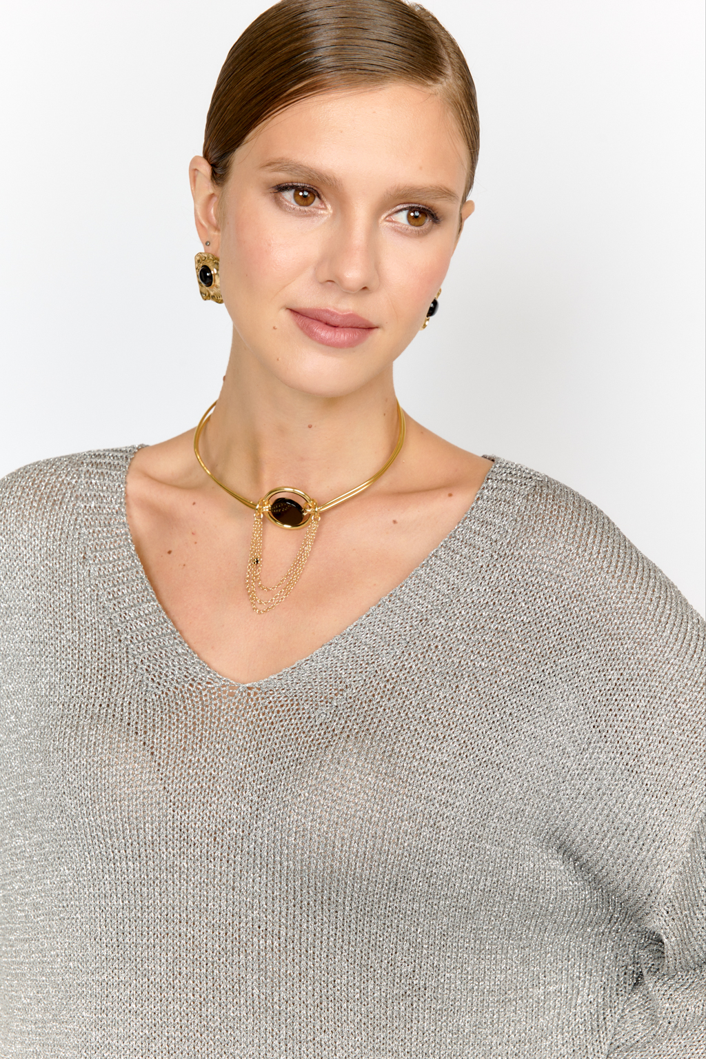 Модель джемпера с V-образным  вырезом горловины и свободным кроем выполнена из премиальной пряжи с вискозой в составе. Металлизированное волокно придает пряже  мерцание. Мягкие ниспадающие линии джемпера красиво драпируют фигуру. Базовая по крою модель, выглядит уникальной  благодаря эффектному металлизированному блеску и серо-серебряному цвету пряжи. Элегантный силуэт с длиной выше бедер и изящным V-образным вырезом подчеркивает женственность и создает безупречный образ.