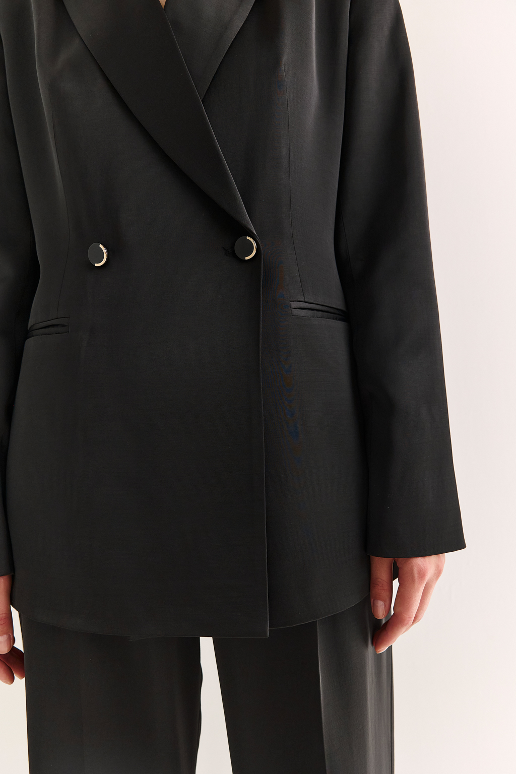Двубортный жакет: классика в современной геометрии
Удлинённый двубортный жакет — это база, которая говорит о статусе без слов. Чёткие плечи, графичный крой и острые лацканы формируют уверенный, собранный образ. Рельефы по спинке и бокам подчёркивают силуэт, обеспечивая идеальную посадку, а карманы добавляют практичности и сдержанного акцента.
Идеален в паре с классическими брюками, юбкой-карандашом или джинсами. Работает как в деловом комплекте, так и в вечерней стилизации.
Современная структура с уважением к традиции.