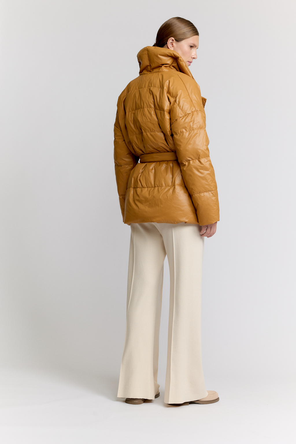 Короткий стеганый пуховик с английским воротником в горчичном цвете, застегивается на кнопки, имеет регулируемый пояс, что позволяет носить изделие в разных вариациях.
