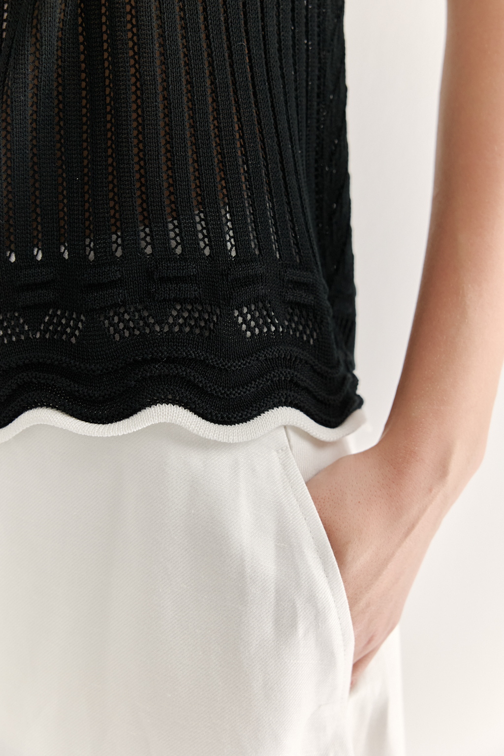 Черный топ в стиле пэчворк, в котором соединились четыре техники ажурной вязки, круглая горловина и деликатные рюши по пройме. Контрастная отделка расположена по линиям горловины, низа и краю рюши.