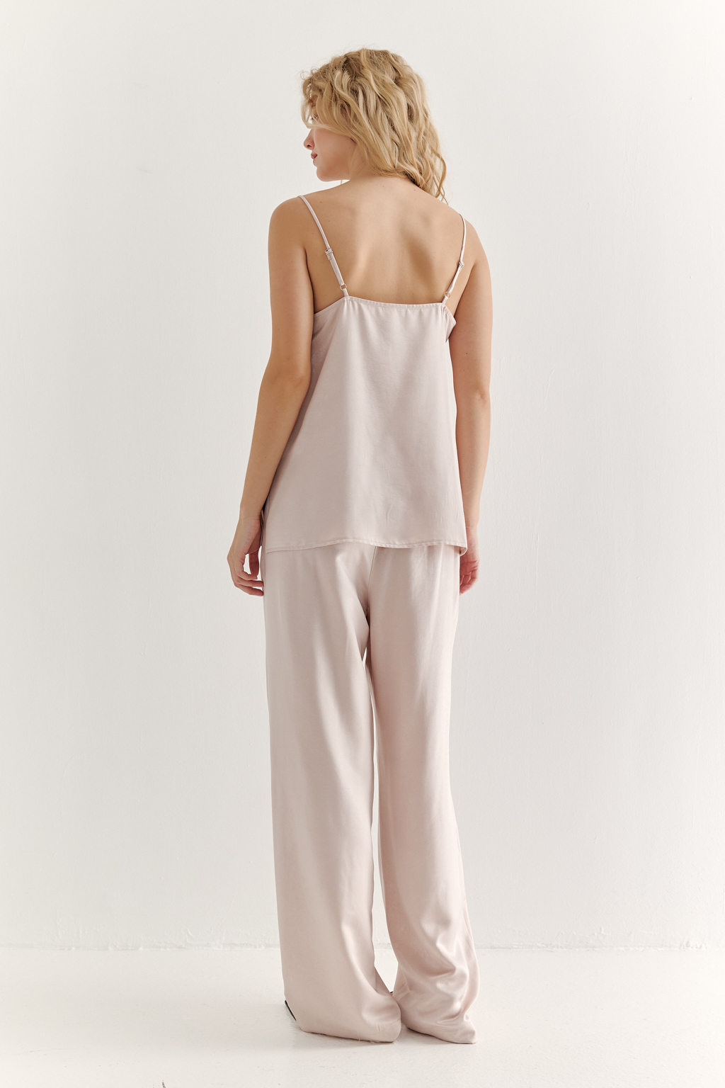 Топ из струящегося атласа с крэш эффектом в пудровом цвете. Топ на регулируемых бретелях свободного кроя с декором на линии декольте.