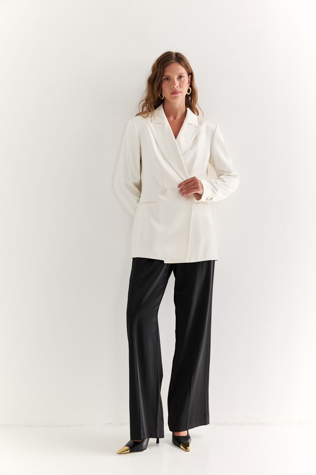 Двубортный жакет: классика в современной геометрии. Удлинённый двубортный жакет — это база, которая говорит о статусе без слов. Чёткие плечи, графичный крой и острые лацканы формируют уверенный, собранный образ. Рельефы по спинке и бокам подчёркивают силуэт, обеспечивая идеальную посадку, а карманы добавляют практичности и сдержанного акцента. Идеален в паре с классическими брюками, юбкой-карандашом или джинсами. Работает как в деловом комплекте, так и в вечерней стилизации. Современная структура с уважением к традиции.