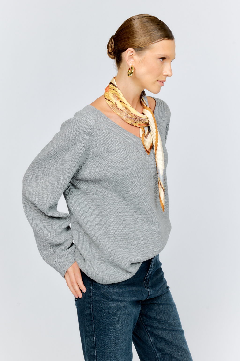 Трикотажный джемпер серого цвета свободного силуэта с V-образным вырезом горловины и рукавами реглан из шерстяной смесовой пряжи станет центром комфортных осенних образов.