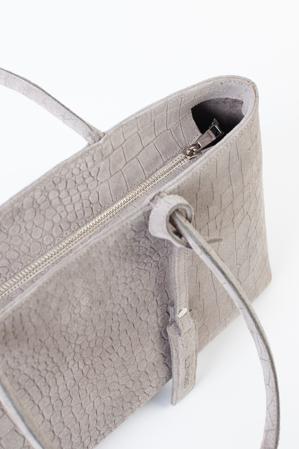 Сумка-тоут выполнена из высококачественного натурального спил-велюра с теснением под рептилию. Аксессуар закрывается на металлическую молнию, имеет удобные ручки и брелок. Размеры сумки: 45*21*5,8 см.