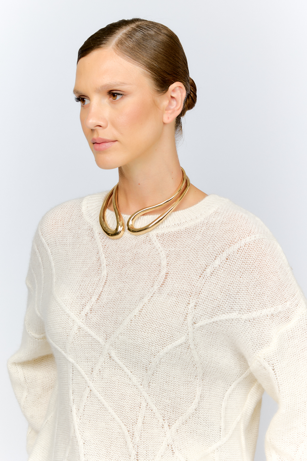 Нежный молочный  джемпер из мягкой шерстяной пряжи с трендовым ажурным дизайном, круглой горловиной, со спущенной линией плеча и длинными рукавами имеет  свободный силуэт оверсайз. Уникальный узор привлекает внимание и придает образу стильный акцент.
