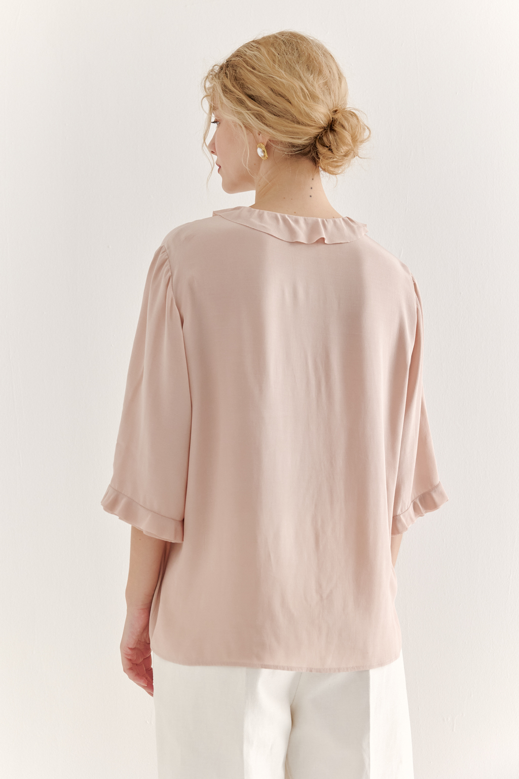 Эта романтичная блуза выполнена из вискозного крепа в нежном пудрово-розовом оттенке. Горловина и рукава украшены изящными рюшами, добавляющими образу легкости и утонченности. Оригинальный разрез спереди кокетливо завязывается на тонкий шнур-рулик и фиксируется воздушной петлей на пуговицу. Прямой силуэт и рукава длиной одна вторая обеспечивают комфорт и свободу движений. Эта блуза — идеальный выбор для создания непринужденных, но элегантных городских образов.