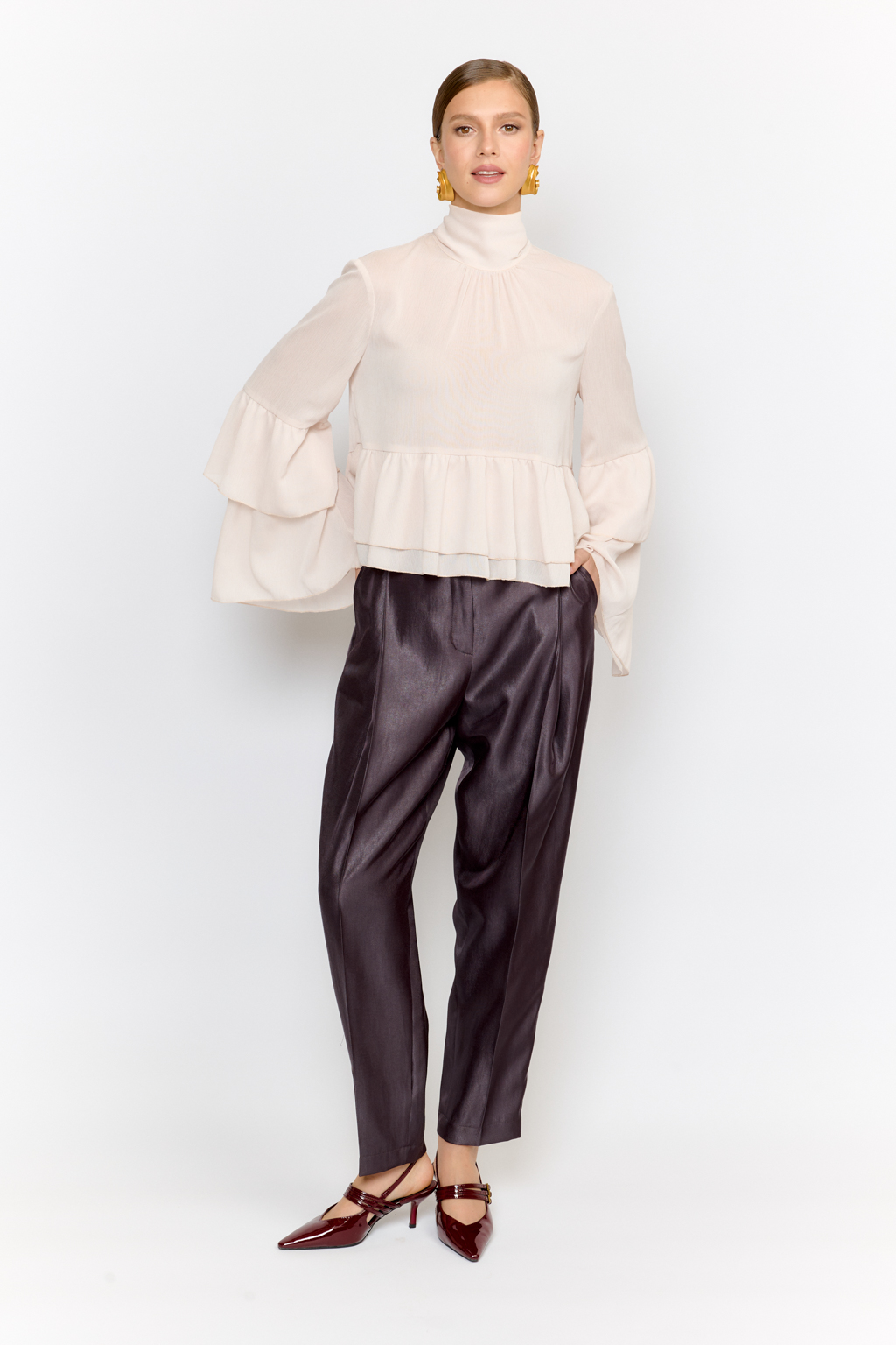 Блуза свободного кроя с легким расширением к низу с воланами и воротником-стойкой, переходящим в ленты, которые можно завязать в бант либо просто перекинуть через плечи. Выполнена из легкой полупрозрачной ткани. Крэш-шифон -легкий, дышащий материал, создающий эффект невесомости. Полиэстеровые волокна в составе обеспечивают   неприхотливость в уходе и устойчивость к механическим повреждениям. Нежный цвет экрю позволяет легко вписать блузу в гардероб, для создания как праздничных образов, так и повседневных.