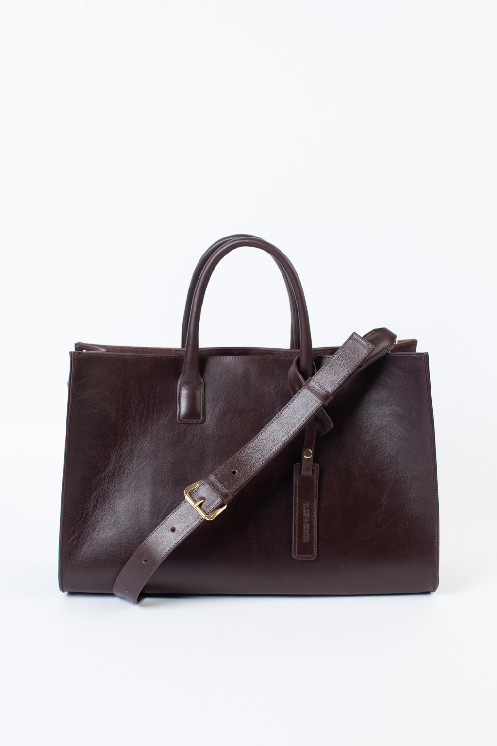 Стильная сумка через плечо глубокого шоколадного оттенка станет незаменимым спутником вашей коллекции. Простая, лаконичная форма идеально впишется в деловой образ. Вместительная модель выполнена из натуральной гладкой кожи с ручками сверху и дополнена ремешком через плечо. Размеры сумки: 39,7*25*14 см.