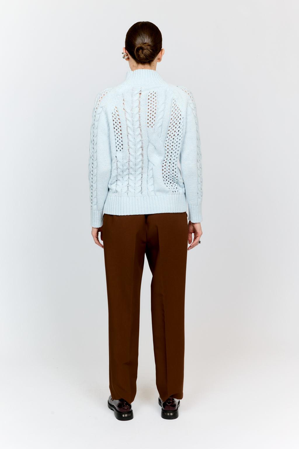 Свитер голубого цвета из мягкой пряжи фигурной вязки с ассиметричными косами, с высокой горловиной и длинным рукавом реглан отлично стилизуется с денимом и обувью на плоском ходу.