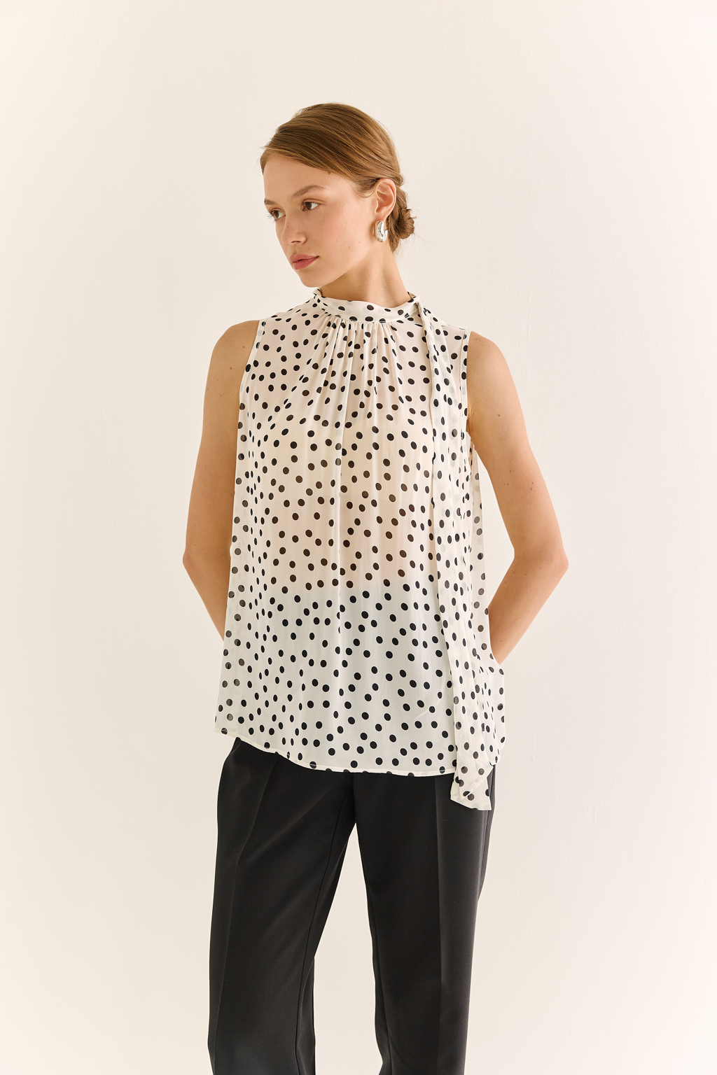 Блузка с бантом: женственность и утончённый акцент. Эта блузка без рукавов — воплощение элегантной простоты с выразительной деталью. Горловина украшена мягким бантом, который добавляет образу нотки утончённости и романтичного шика. Лёгкая драпировка спереди делает силуэт свободным, но изящным, подчёркивая вкус и стиль. Идеальна для офисных будней, деловых встреч или вечерних образов. Эффектно смотрится под жакет или кардиган, но и сама по себе становится акцентом. Сила — в деталях. Женственность — в каждом движении.