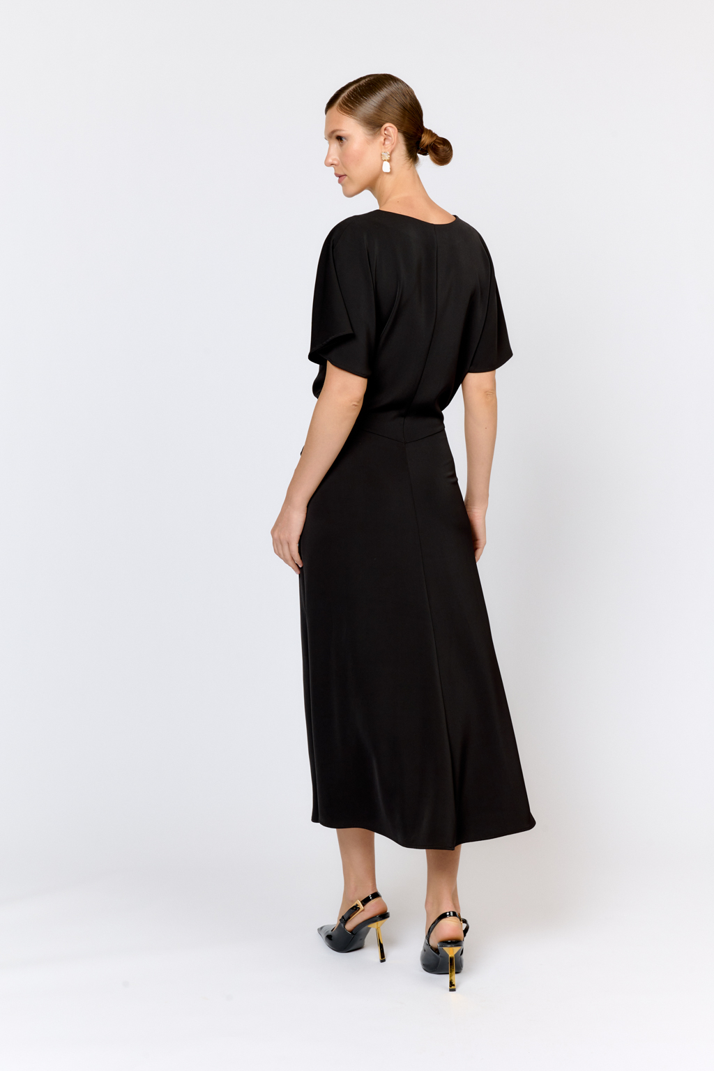 Струящееся платье свободного кроя с цельнокроеными рукавами и открытой горловиной с V-образным вырезом горловины. Модель с декоративной пряжкой на притачном поясе со сборкой по бокам. Выполнено из эластичной плательной ткани. Полиэстер придает ткани устойчивость к сминанию и хорошо держит форму. Что позволяет изделию сохранять опрятный вид в течении дня.  Глубокий черный цвет не тускнеет после стирки. Спандекс добавляет эластичность, обеспечивая идеальную посадку по фигуре. Преимущества ткани: новое современное качество с мягким блеском и благородной фактурой. Ткань легкая, приятна к телу, красиво драпируется при движении. Глубокий черный оттенок придает изделию благородный вид.