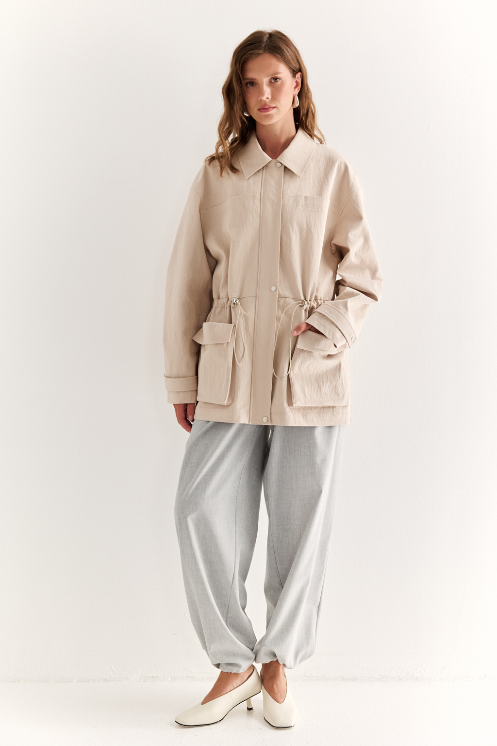 Куртка прямого силуэта длиной до бедер и с кулисой по талии. Воротник рубашечный, застежка под планкой. По полочке накладные карманы-портфели.