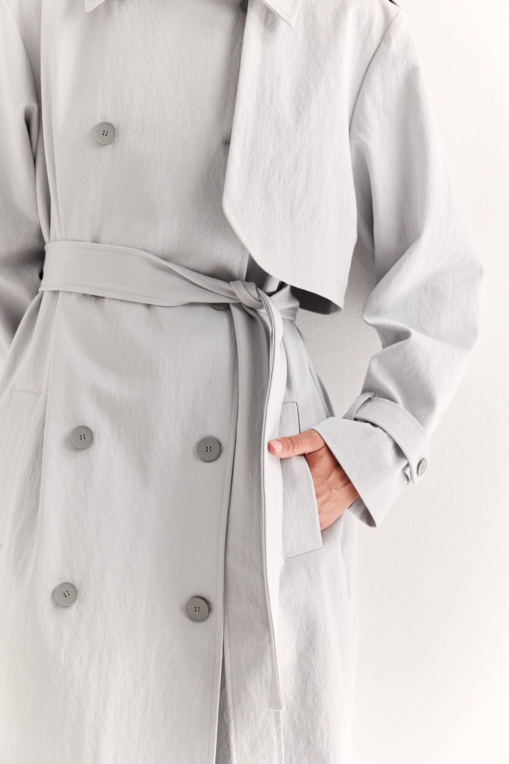 Плащ двубортный прямого силуэта длиной макси с расширенной линией плеча и отлётными кокетками по полочке и спинке. Приталивается завязывающимся поясом.