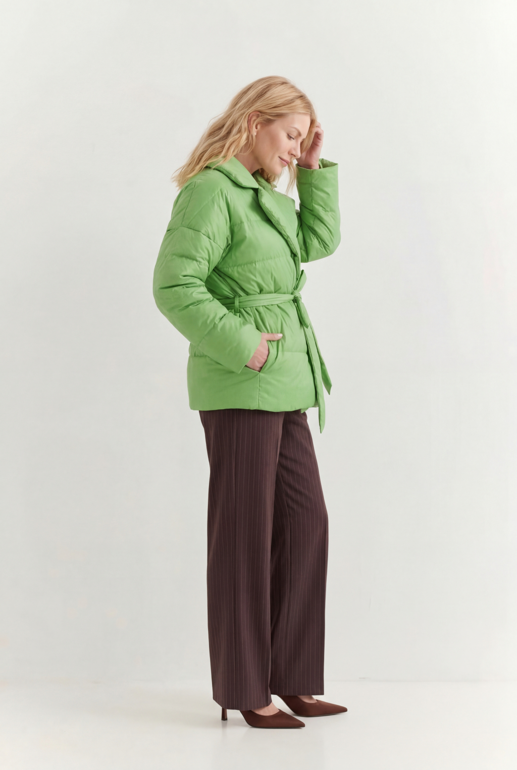 Короткий стеганый пуховик с английским воротником в цвете зеленой мяты, застегивается на кнопки, имеет регулируемый пояс, что позволяет носить изделие в разных вариациях.