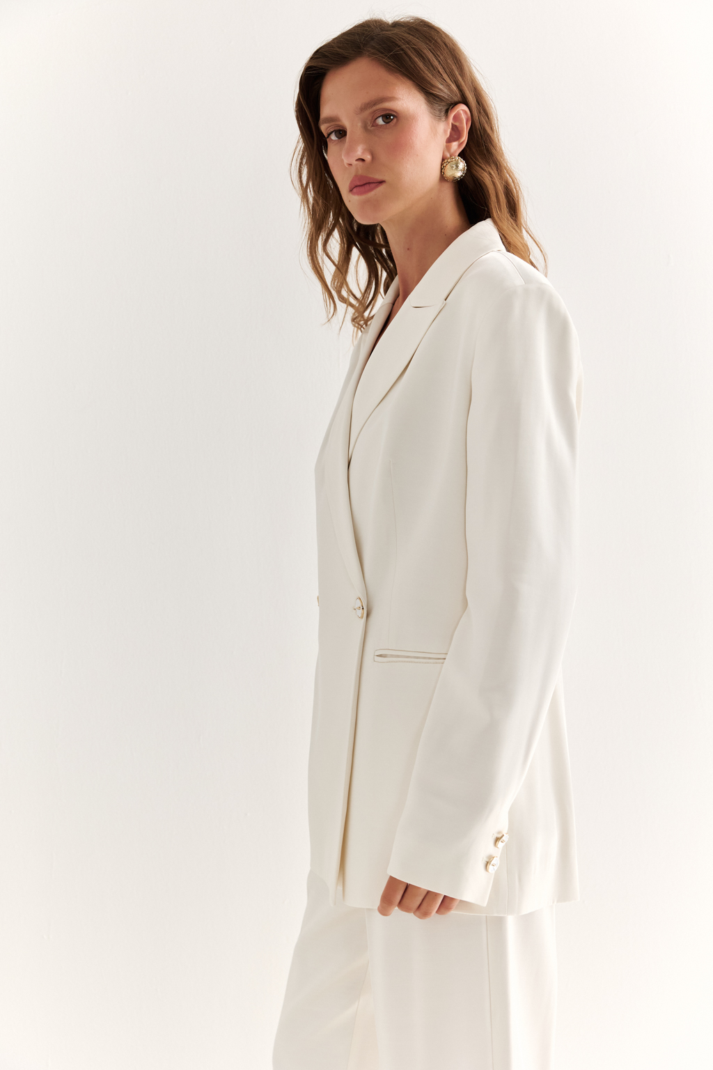 Двубортный жакет: классика в современной геометрии. Удлинённый двубортный жакет — это база, которая говорит о статусе без слов. Чёткие плечи, графичный крой и острые лацканы формируют уверенный, собранный образ. Рельефы по спинке и бокам подчёркивают силуэт, обеспечивая идеальную посадку, а карманы добавляют практичности и сдержанного акцента. Идеален в паре с классическими брюками, юбкой-карандашом или джинсами. Работает как в деловом комплекте, так и в вечерней стилизации. Современная структура с уважением к традиции.