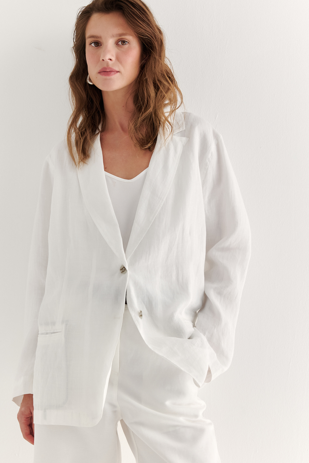 Жакет, выполненный из стопроцентной крапивы благородного молочного оттенка, отличается эффектом прозрачности и текстуры мятости. Дизайн модели вдохновлен классическим мужским пиджаком. Необычная тонкая прозрачная и жатая ткань придает его форме мягкое и тактильное звучание. Особое внимание уделено отделке внутренней части: внутренние швы искусно окантованы контрастной тканью, тщательно проработаны мешковины карманов, предусмотрена частичная подкладка. Все это делает дизайн жакета одновременно неожиданным и сложным. Однако подлинный смысл этого изделия раскрывается лишь изнутри, едва просвечивая сквозь поверхность. Снаружи – это все тот мужской пиджак: классический воротник с лацканом, карманы в рамку и застежка на две пуговицы, только средний шов спинки представляет собой настроченную налицо кромку ткани.
Отлично подходит для создания многослойного образа, выбирайте брюки из льна или крапивы в качестве компаньона.